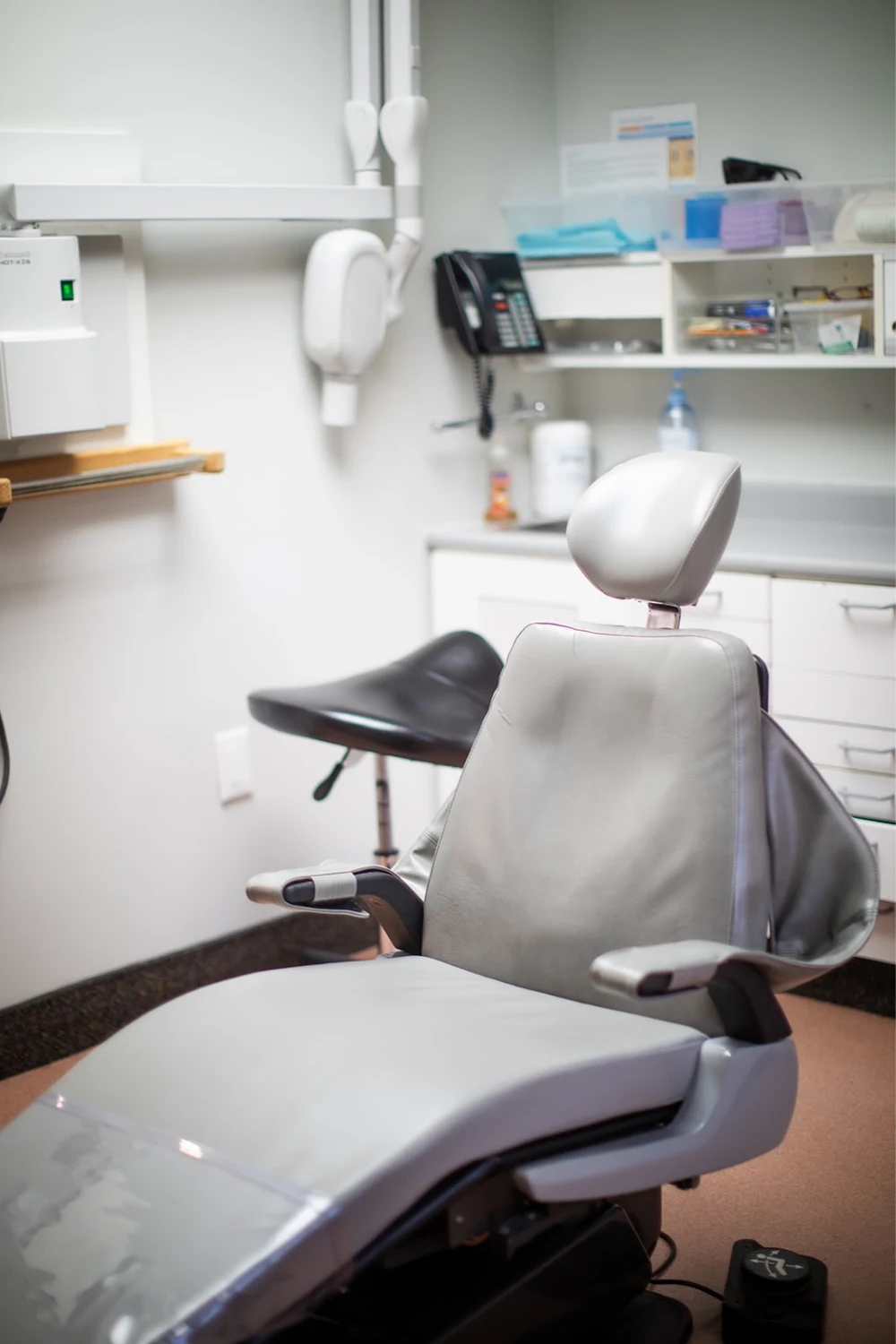 A dental treatment chair and equipment beside a bright window